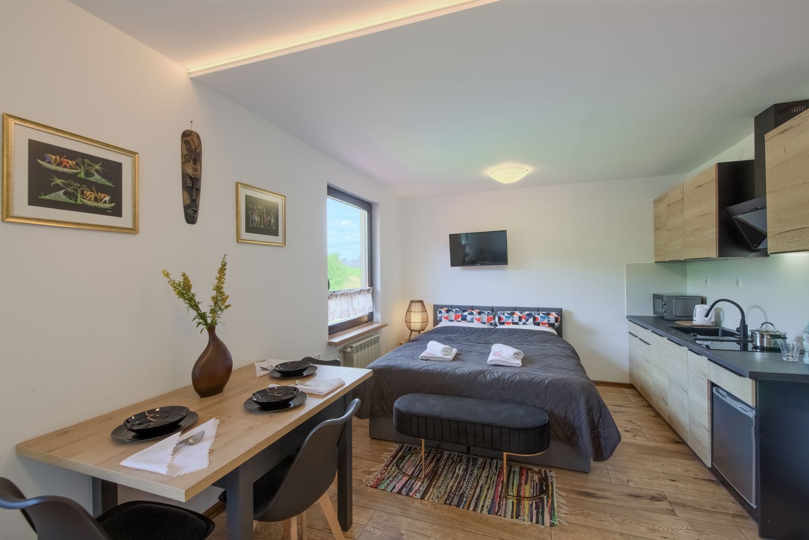 Apartament Afrykański w Willi OdNova Tylicz: nakryty stół na cztery osoby, łóżko małżeńskie i aneks kuchenny