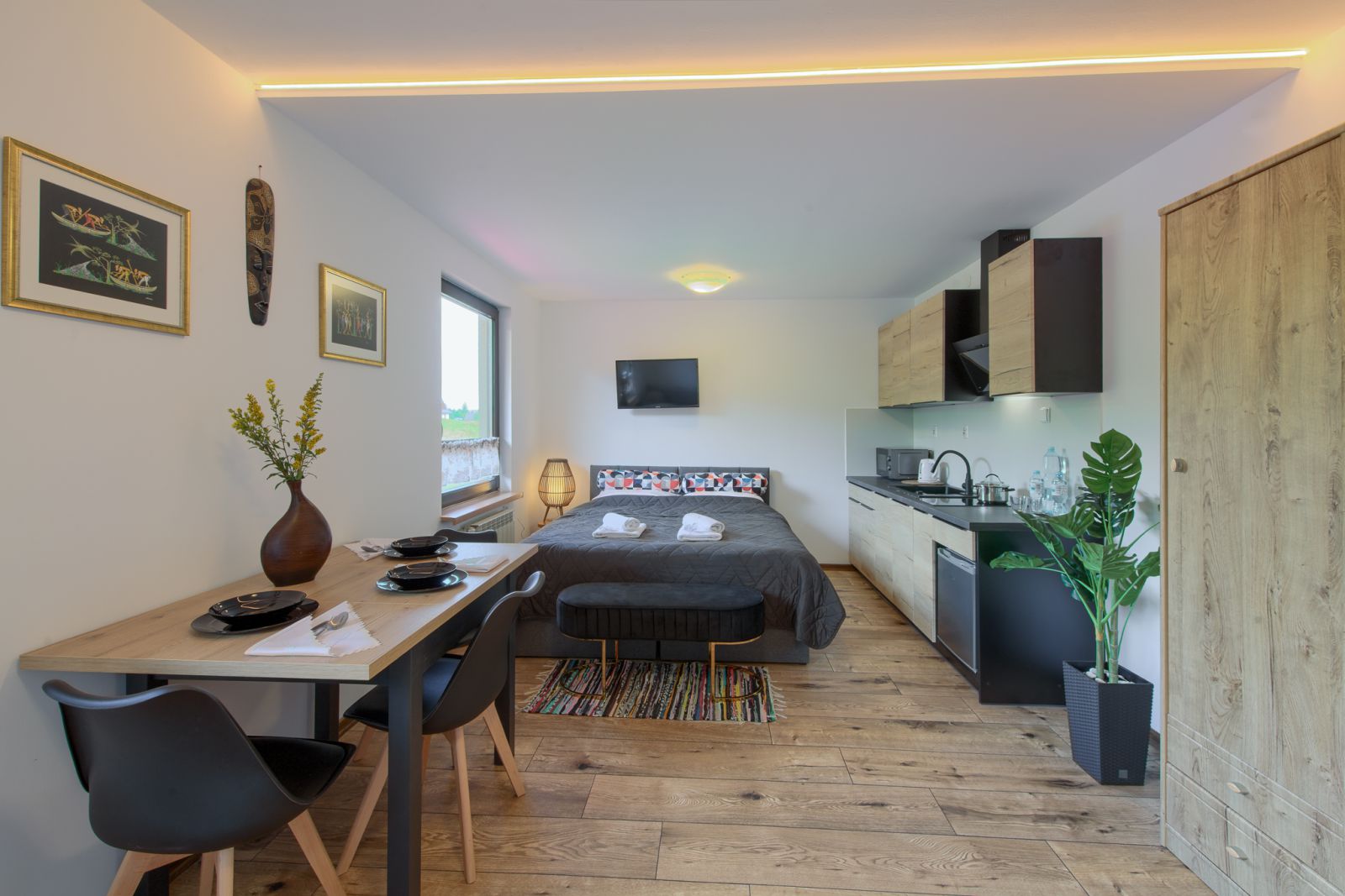 Apartament Afrykański w Willi OdNova Tylicz: łóżko małżeńskie, stół jadalny, aneks kuchenny i afrykańskie dekoracje