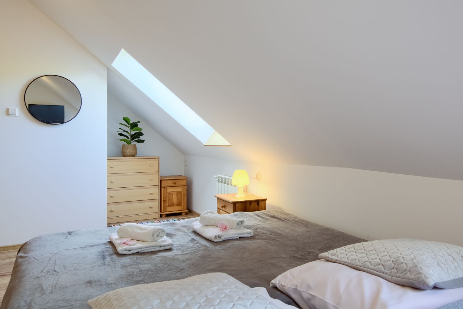 Łóżko, komoda i lampka nocna pod skosem w Apartamencie Balonowym Willi OdNova Tylicz