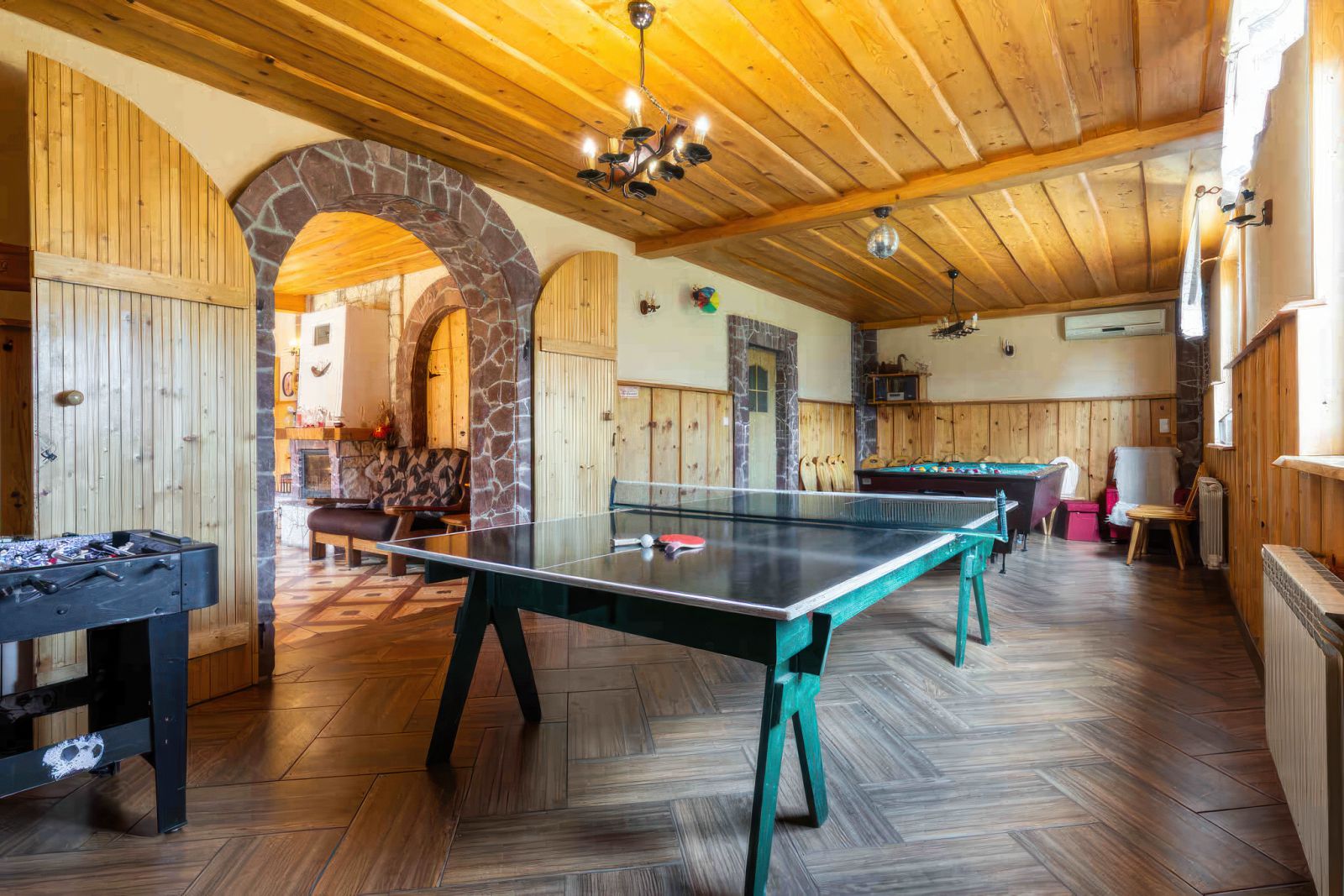 Sala rekreacyjna Willi OdNova z stołem do ping-ponga, kominek, drewniany sufit i kamienne łuki