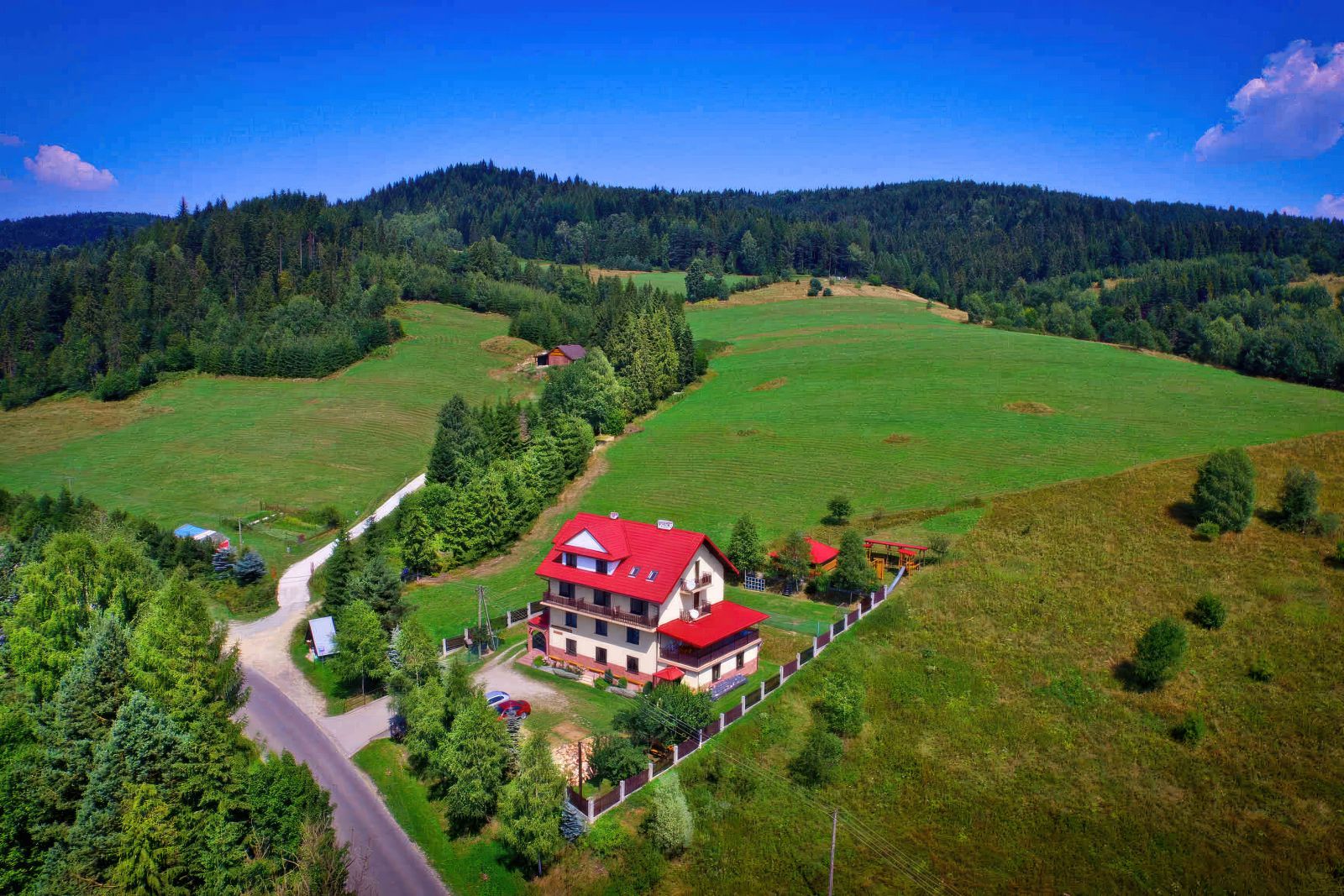 Lot ptaka na Willę OdNova w Tyliczu - czerwony dach, otoczona zielenią, Beskid Sądecki w tle