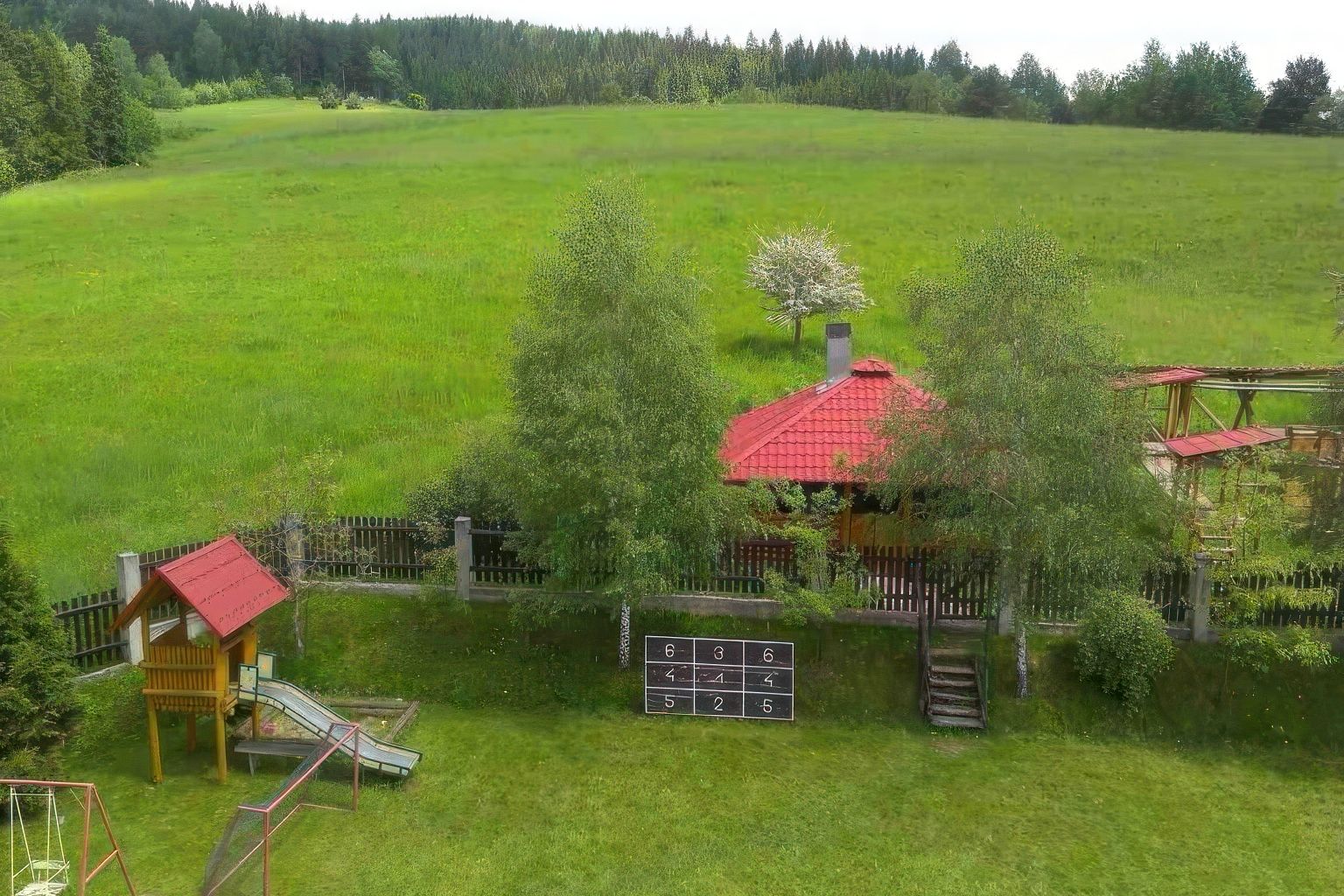 Ogród Willi OdNova z placem zabaw dla dzieci, huśtawkami, zielonym polem i lasem